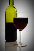 Zelená láhev a sklenice červeného vína