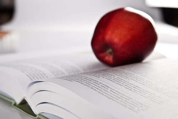 Opened hefty book and red apple — Stock Photo, Image