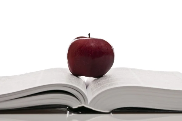 Открытая здоровенная книга и красное яблоко — стоковое фото