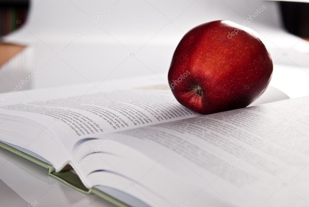 Open hefty book and fresh red apple