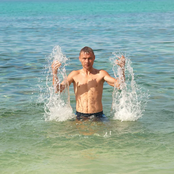Glücklicher Mann im Meer mit Spritzern — Stockfoto