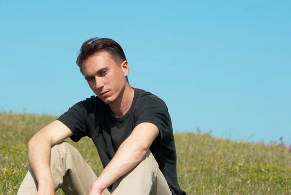 Ung man sitter på gräsplan — Stockfoto