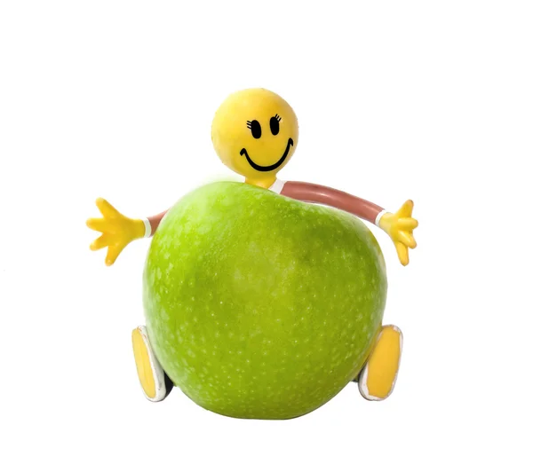 Juguete de goma poco hombre sostiene una manzana Rechtenvrije Stockfoto's