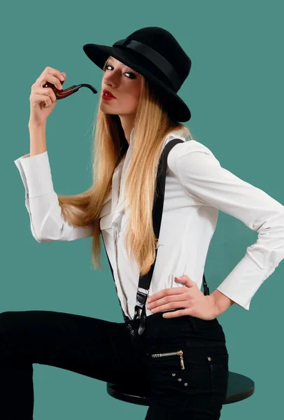 Den unga kvinnan i en hatt med en rör — Stockfoto