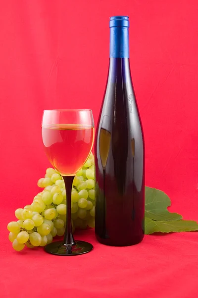 Κρασί και σταφύλια σε κόκκινο φόντο — Φωτογραφία Αρχείου