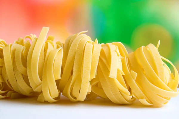 Rad torr kapsla pasta på färgad bakgrund — Stockfoto