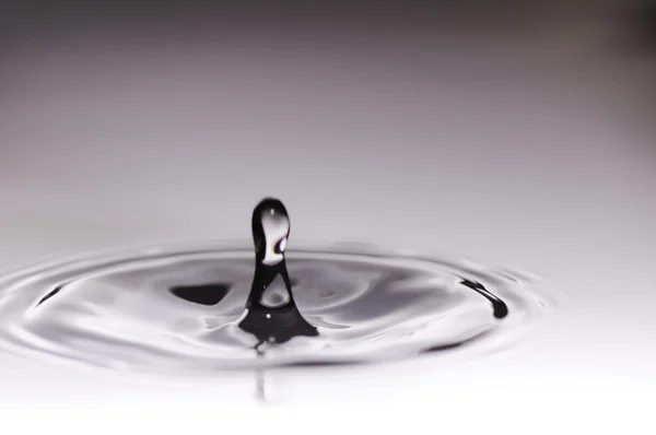 Water drop in rippled liquid close-up — Stock Photo, Image
