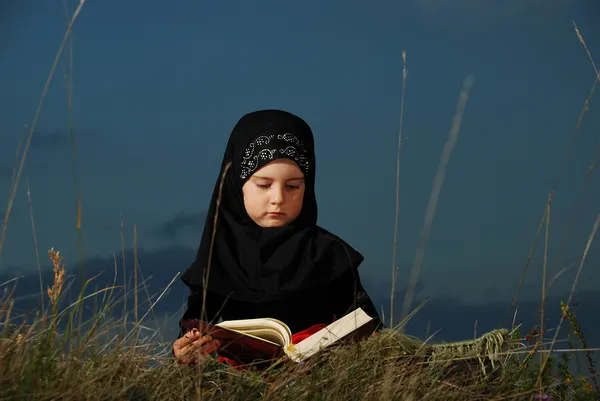 Una pequeña chica musulmana linda leyendo el libro sagrado Kora —  Fotos de Stock