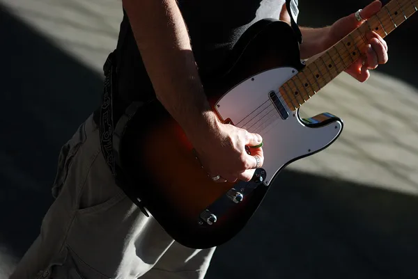 Masculino jogar um guitarra contra escuro backg — Fotografia de Stock