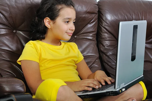 Menina bonita em leitura amarela no laptop — Fotografia de Stock