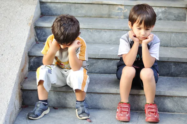 Два грустных ребенка на ступеньках — стоковое фото