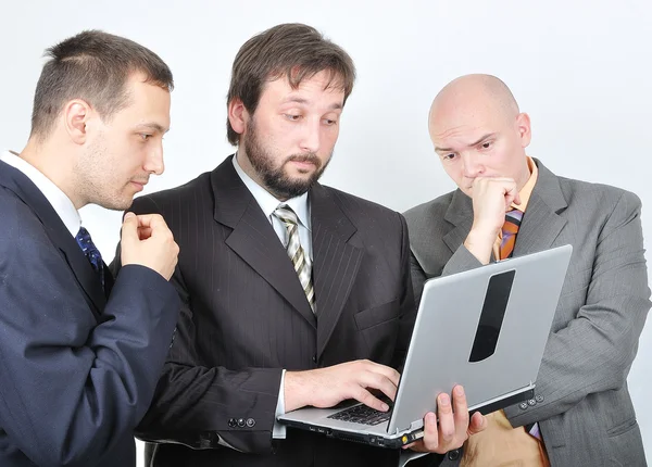 Grupo de três jovens empresários no computador portátil — Fotografia de Stock