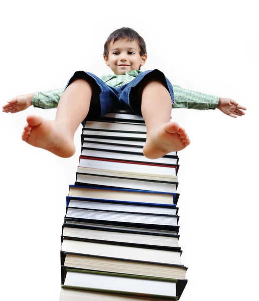 Um pequeno garoto bonito e grande número de livros — Fotografia de Stock