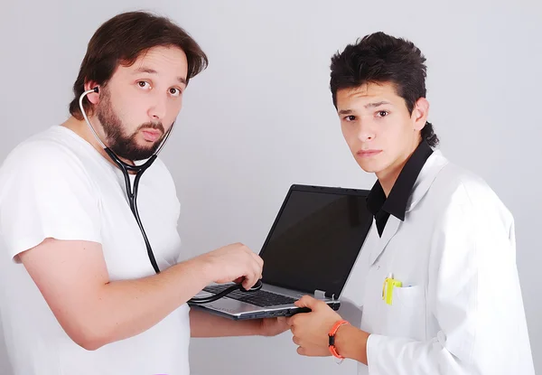 Twee grappige mannelijke artsen met laptop in handen — Stockfoto