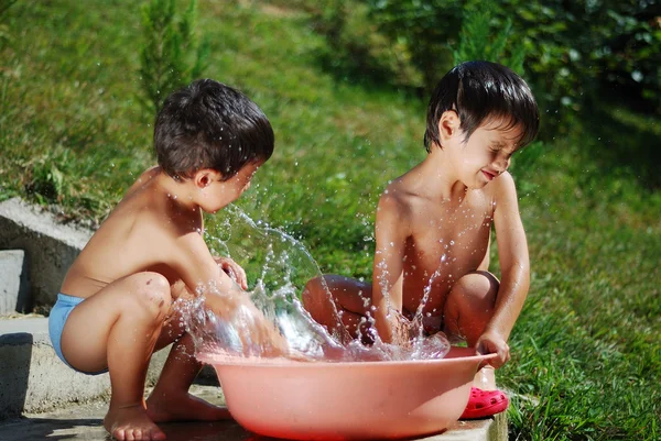 Mycket söta barn leker med vatten överträffa — Stockfoto