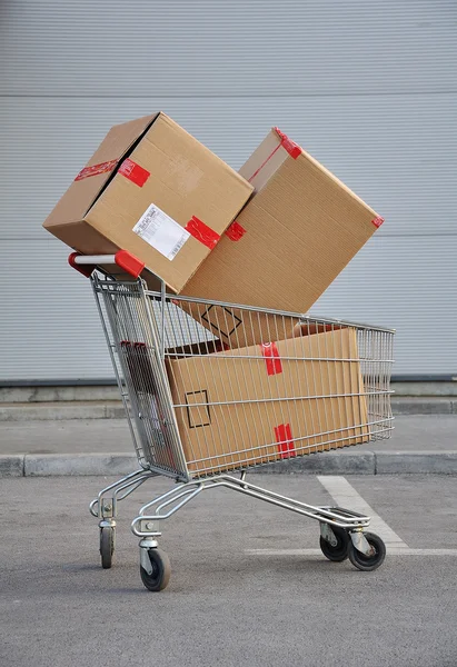 Roda de compras com caixas em — Fotografia de Stock