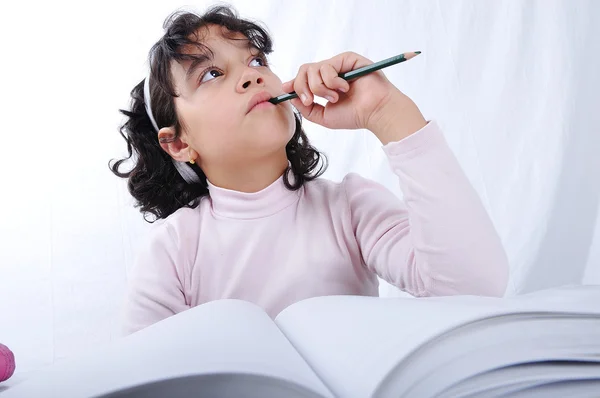 En liten söt flicka skriver på anteckningsboken — Stockfoto