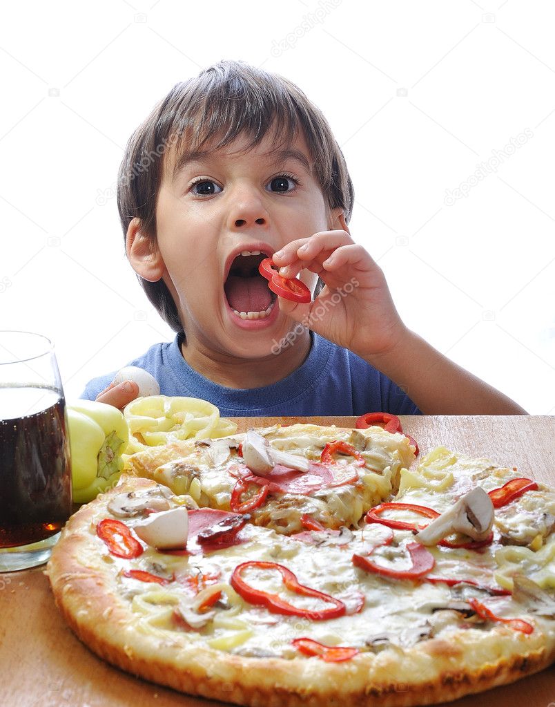 Cute little boy eating pizza on table, i