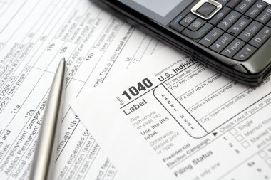 Mobile phone and pen on tax forms clipart