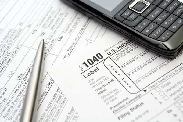 Мобильный телефон и ручка на налоговых бланках — стоковое фото