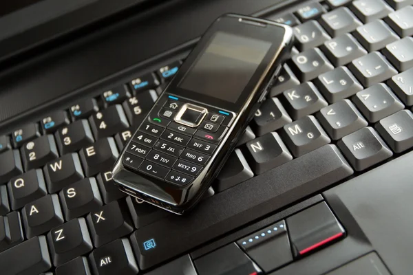 Мобильный телефон и клавиатура ноутбука — стоковое фото