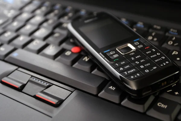 Мобильный телефон и клавиатура ноутбука — стоковое фото