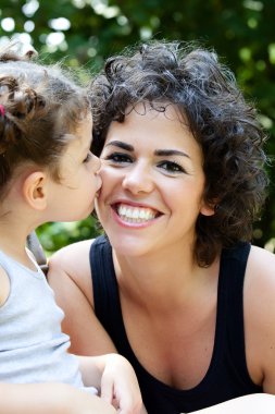 Daughter kissing her smiling mother clipart