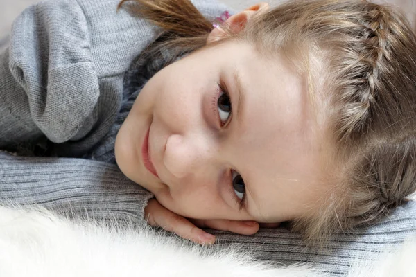 Lächelndes Mädchen auf einem Pelz liegend — Stockfoto