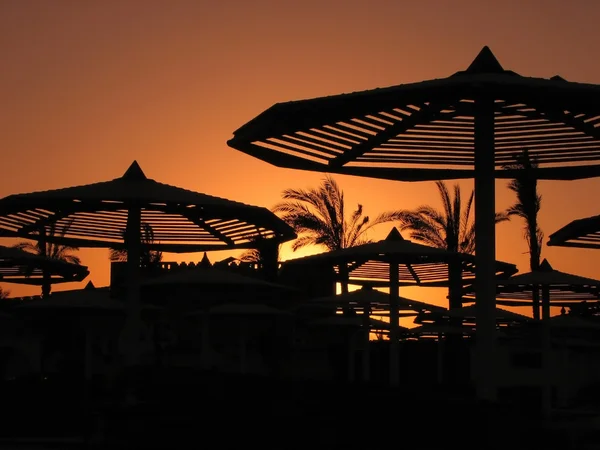 Sunset with beach umbrellas — Stock Photo, Image