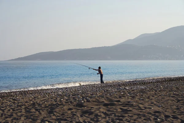 Gün batımında sahilde yalnız balıkçı — Stok fotoğraf