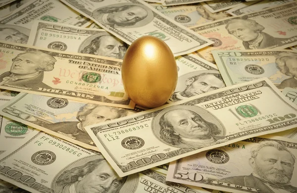Złoty jaj w gnieździe na warstwie gotówki — Zdjęcie stockowe