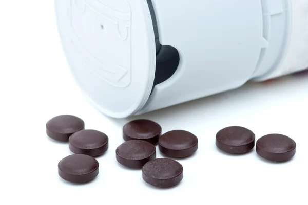 Alguns comprimidos castanhos perto de dispensador de pílulas — Fotografia de Stock