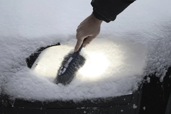 Убрать снег с автомобильной лампы — стоковое фото