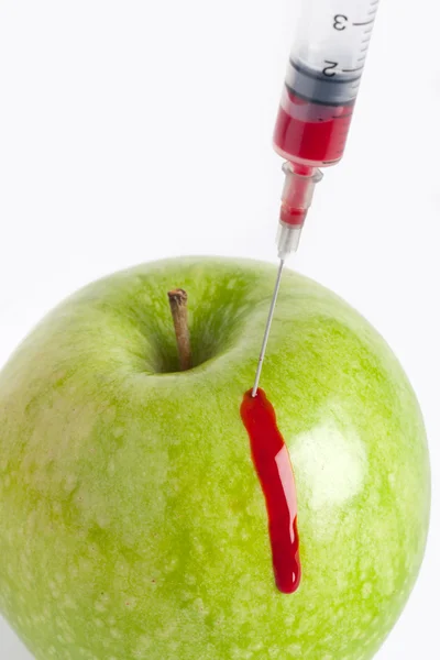 Яблоко и шприц с кровью — стоковое фото