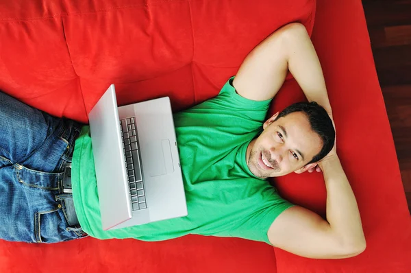 Man ontspannen op de sofa en werk op laptop — Stockfoto
