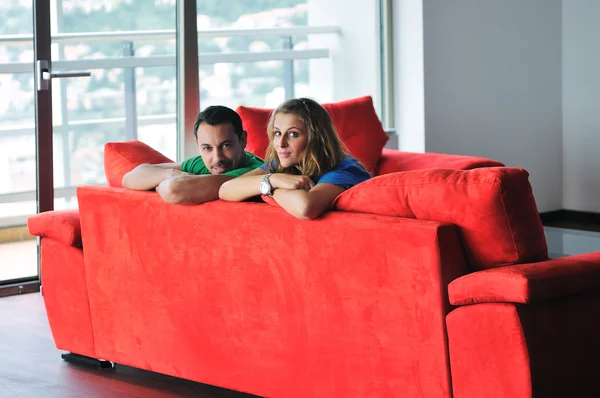 Pareja feliz relajándose en el sofá rojo — Foto de Stock