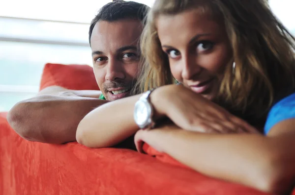 Casal feliz relaxante no sofá vermelho — Fotografia de Stock