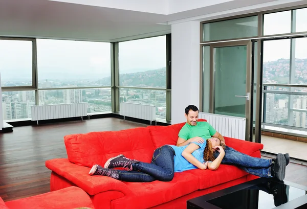 Boldog pár pihentető a piros kanapé — Stock Fotó
