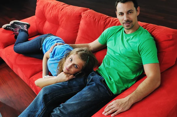 Pareja feliz relajándose en el sofá rojo —  Fotos de Stock