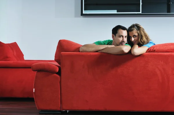 Happy couple relaxing on red sofa — Stock Photo, Image
