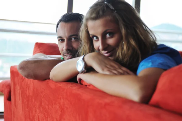 幸せなカップルの赤いソファでリラックス — ストック写真