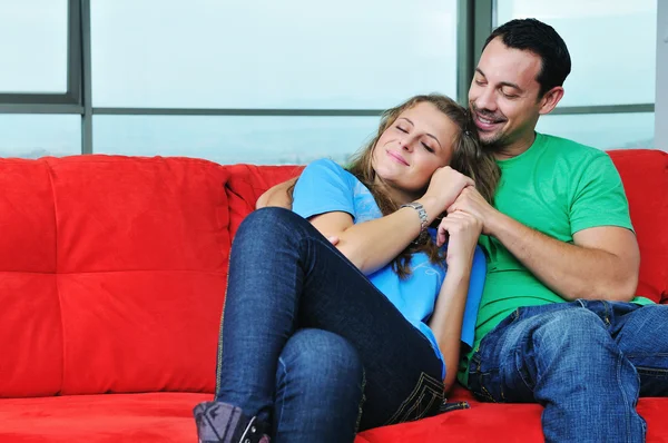 Gelukkige paar ontspannen op rode sofa — Stockfoto