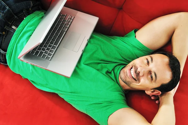 Człowiek wypoczywa na kanapie i pracować na laptopie — Zdjęcie stockowe