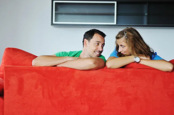 Ευτυχισμένο ζευγάρι χαλαρωτικό σε κόκκινο καναπέ — Φωτογραφία Αρχείου