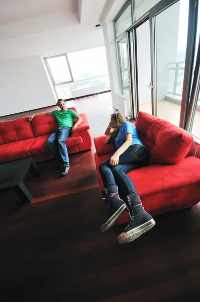 Счастливая пара отдыхает на красном диване — стоковое фото