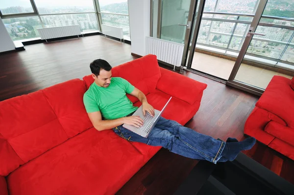 Чоловік розслабляється на дивані і працює на ноутбуці — стокове фото