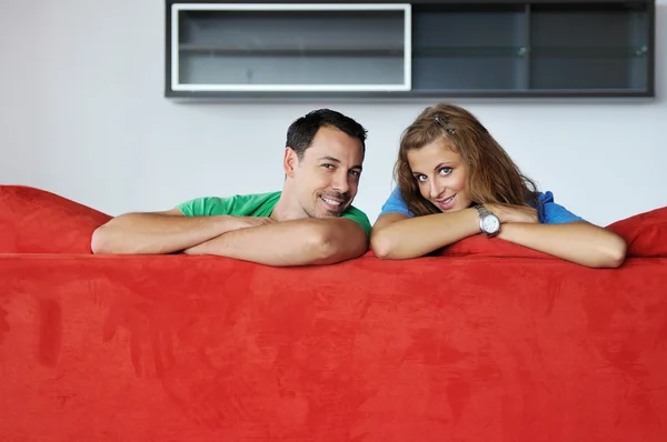 Gelukkige paar ontspannen op rode sofa — Stockfoto