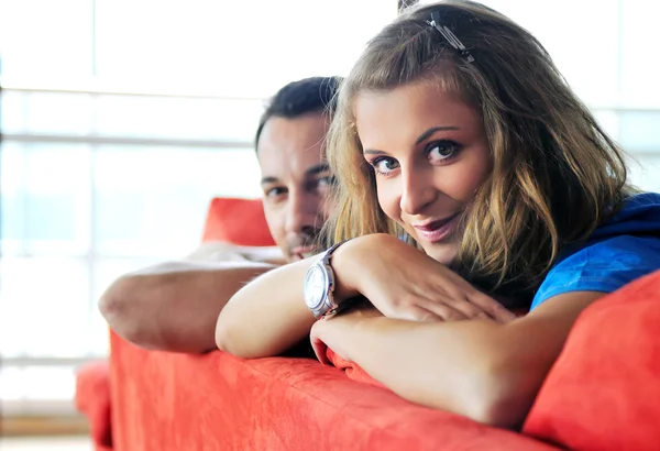 Щаслива пара розслабляється на червоному дивані — стокове фото