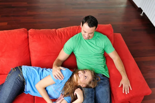 幸福的夫妇在红色沙发上放松 — 图库照片