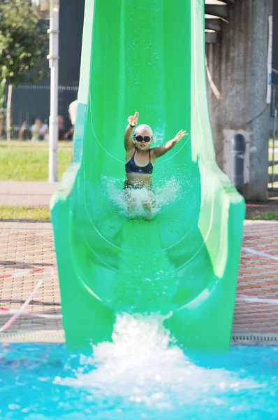 Menina se divertir na corrediça de água na natação ao ar livre — Fotografia de Stock